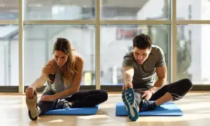 Para ćwiczy stretching, rozciągając nogi na macie. To świetny sposób na poprawę elastyczności.