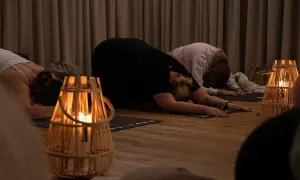 Kobiety w pozycji dziecka na macie do jogi, przy świecach. Uważaj na kundalini niebezpieczeństwa podczas praktyki.