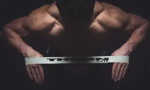 Mięśnie pleców i ramion mężczyzny napinają się podczas ćwiczeń na równowagę z taśmą THORN+FIT.