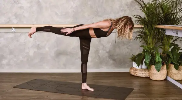 Kobieta w pozycji Virabhadrasana III, ćwicząca mula bandha.