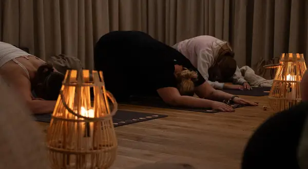 Kobiety w pozycji dziecka na macie do jogi, przy świecach. Uważaj na kundalini niebezpieczeństwa podczas praktyki.