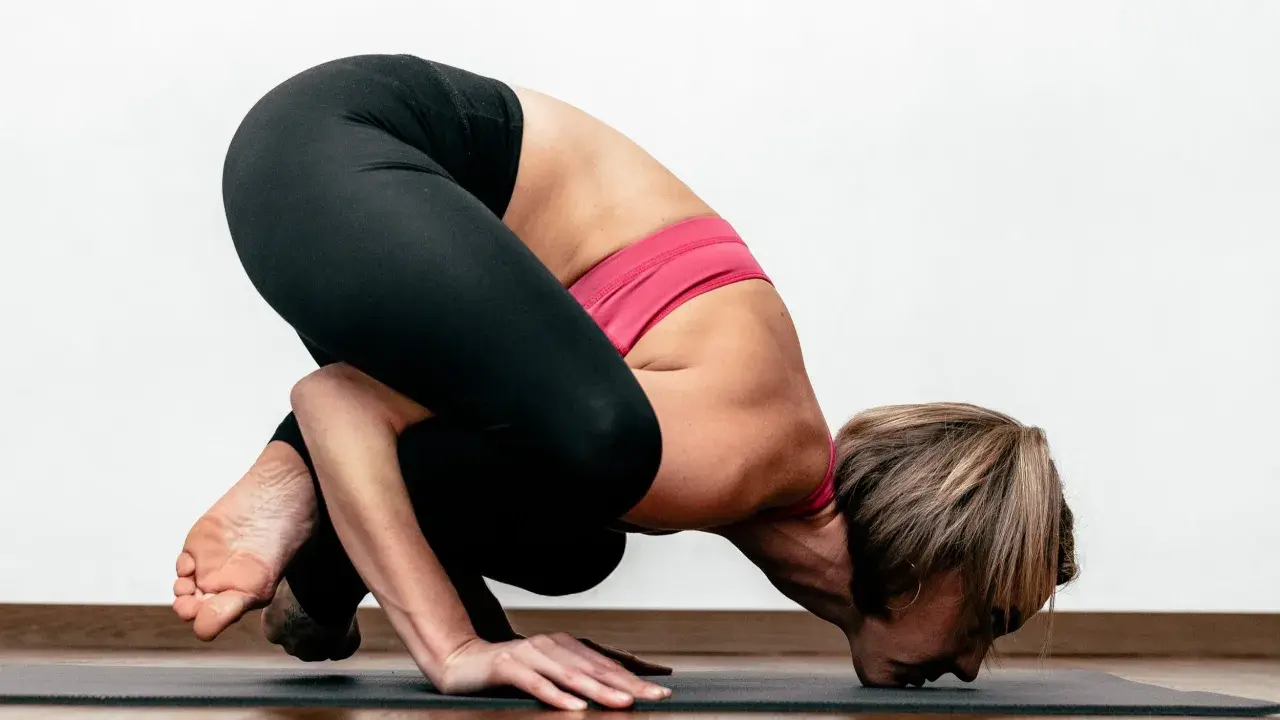 Kobieta w pozycji Bakasana podczas praktyki ashtanga jogi.