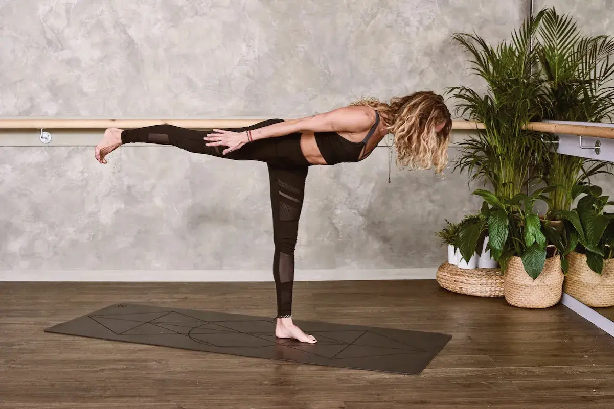 Kobieta w pozycji Virabhadrasana III, ćwicząca mula bandha.