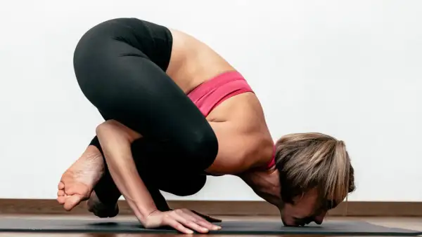 Kobieta w pozycji Bakasana podczas praktyki ashtanga jogi.