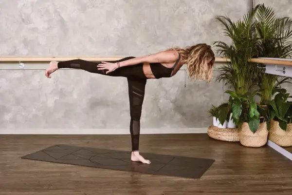 Kobieta w pozycji Virabhadrasana III, ćwicząca mula bandha.