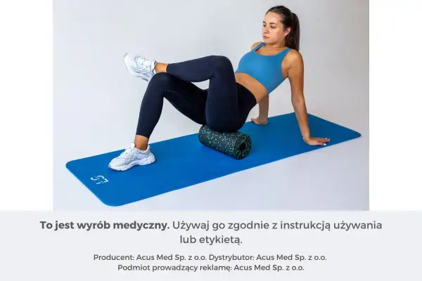 Kobieta na macie rehabilitacyjnej używa wałka do automasażu, by rozluźnić mięsień gruszkowaty.